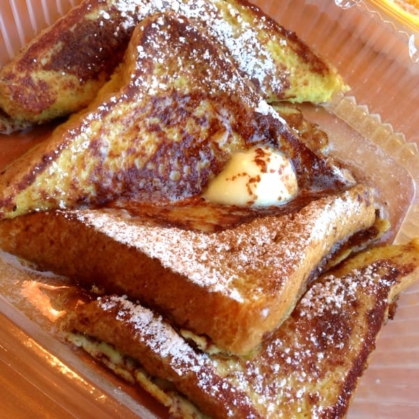 Golden French toast triangles, dusted with powdered sugar and topped with a pat of melting butter.