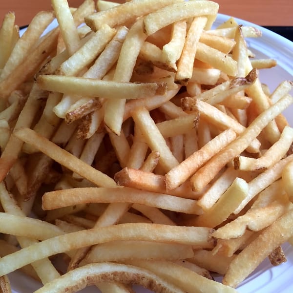 Close-up of a pile of golden-brown Everest Burgers french fries in a white container.